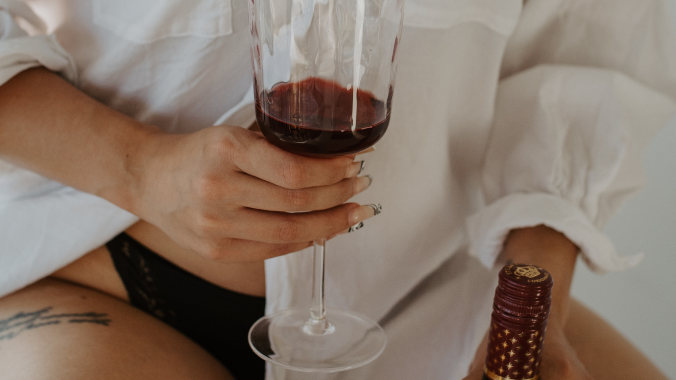 6 Signs Your Feminine Energy May Be Blocked, red wine in glass, woman in white button down shirt